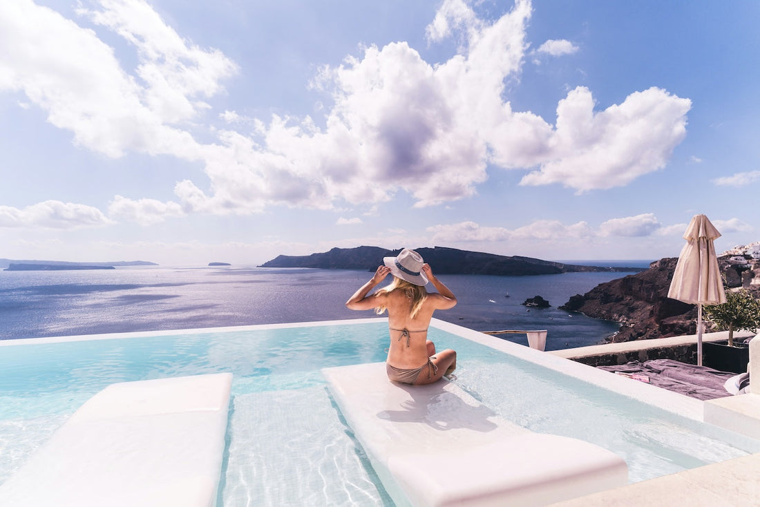 Woman sitting by the pool overlooking blue ocean